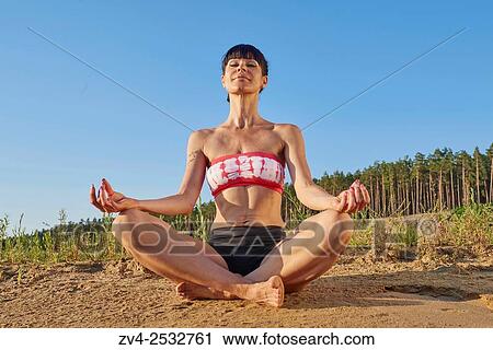 Young woman doing yoga on a beach next to a little lake. View Large Photo Image Stock Image - Young woman doing yoga on a beach next to a little lake.. Fotosearch