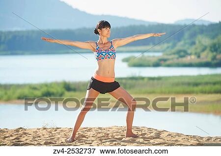 Young woman doing yoga on a beach next to a little lake. View Large Photo Image Stock Photo - Young woman doing yoga on a beach next to a little lake.. Fotosearch