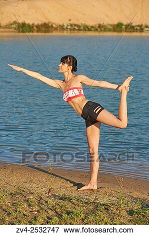 Young woman doing yoga on a beach next to a little lake. View Large Photo Image Stock Photo - Young woman doing yoga on a beach next to a little lake.. Fotosearch