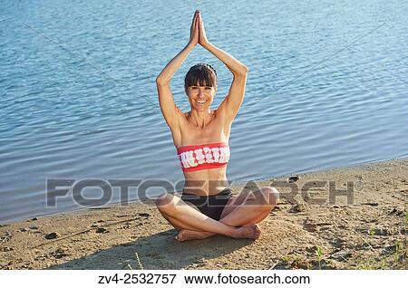 Young woman doing yoga on a beach next to a little lake. View Large Photo Image Stock Photo - Young woman doing yoga on a beach next to a little lake.. Fotosearch