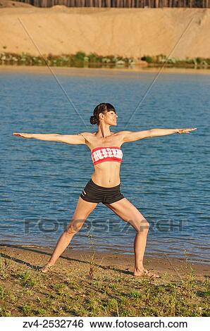 Young woman doing yoga on a beach next to a little lake. View Large Photo Image Stock Photograph - Young woman doing yoga on a beach next to a little lake.. Fotosearch