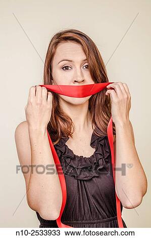 Young woman holding a red ribbon over her mouth. View Large Photo Image Stock Image - Young woman holding a red ribbon over her mouth.. Fotosearch