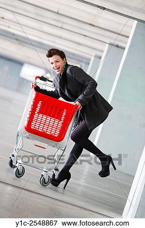 Stock Photo - Young woman shopper with empty cart. Fotosearch