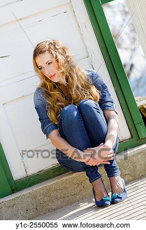 Stock Photography - Young woman sitting embracing legs. Fotosearch