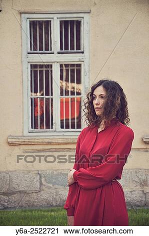 Stock Image - Young woman standing outdoors looking at distance.. Fotosearch