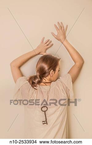 Young woman wearing a large metal key around her neck on her back. View Large Photo Image Picture - Young woman wearing a large metal key around her neck on her back.. Fotosearch