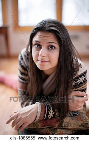 Stock Photography - 20-something, olive skinned, long hair girl laying on the floor and looking at the camera.. Fotosearch