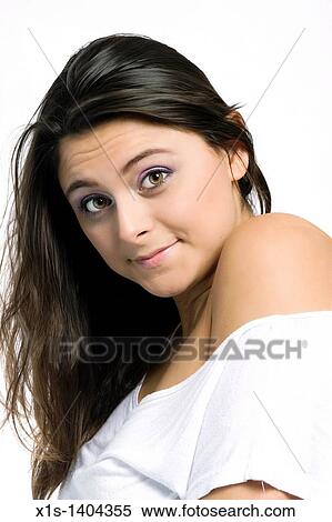 Stock Photography - A long haired, pretty girl dressed in a tight fitting, bare shoulder, white top looks toward the camera, her head tilted toward and a soft smile on her face.. Fotosearch
