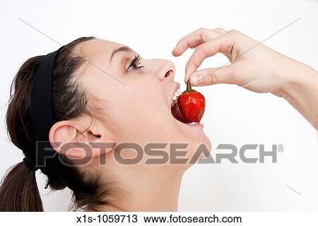A young woman is about to take a bite out of a red pepper she is holding View Large Photo Image Stock Image - A young woman is about to take a bite out of a red pepper she is holding. Fotosearch
