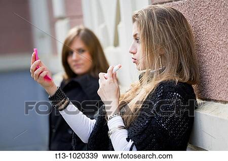 Ad hoc applying makeup with a friend watching View Large Photo Image Stock Photo - Ad hoc applying makeup with a friend watching. Fotosearch