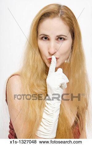 An American woman with long blonde hair wearing long white gloves holds one finger to her lips to silence the viewer. View Large Photo Image Stock Photo - An American woman with long blonde hair wearing long white gloves holds one finger to her lips to silence the viewer.. Fotosearch