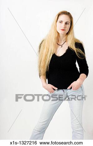 Attractive woman in blue jeans and black casual top has her legs spread and hands in both pockets as she looks away. View Large Photo Image Stock Photograph - Attractive woman in blue jeans and black casual top has her legs spread and hands in both pockets as she looks away.. Fotosearch