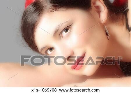 Attractive young woman with her head in her arms looks toward the viewer. View Large Photo Image Stock Photo - Attractive young woman with her head in her arms looks toward the viewer.. Fotosearch