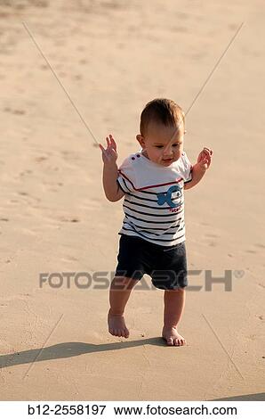 Stock Photo - Baby on the beach - First steps on the sand.. Fotosearch