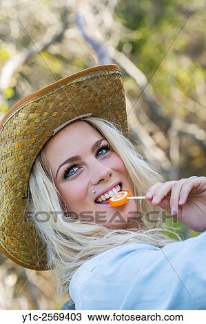 Stock Image - Beautiful blonde countrygirl portrait with lollipop in mouth. Fotosearch