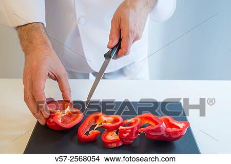 Chef´s hands cutting red pepper on the chopping board. Close view. View Large Photo Image Picture - Chef´s hands cutting red pepper on the chopping board. Close view.. Fotosearch