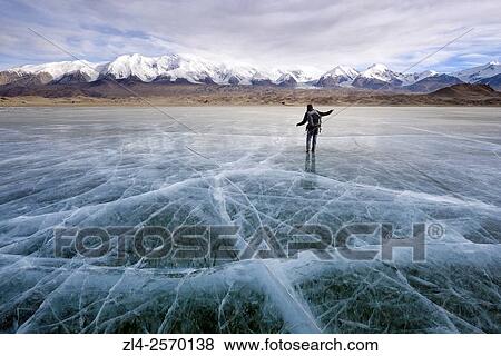 Stock Photo - China, Xinjiang Uyghur Autonomous Region, woman hiking on the frozen Karakul lake (3600m) in winter, Model Released.. Fotosearch