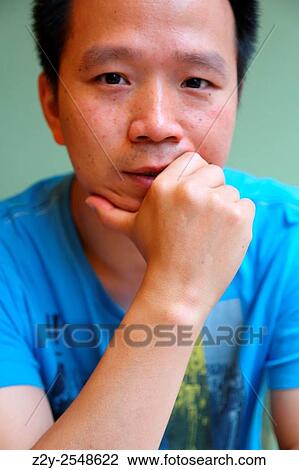 Chinese young guy looking at the camera with his hand supporting his head. View Large Photo Image Stock Image - Chinese young guy looking at the camera with his hand supporting his head.. Fotosearch