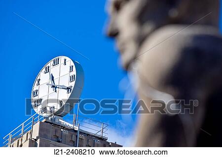 Stock Image - Clock, blurred face of statue, blue sky. PlaÃ§a Catalunya, Barcelona, Catalonia, Spain.. Fotosearch