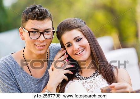 Stock Photo - Girl and boy listen to cellphone together. Fotosearch