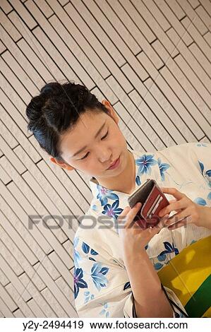 Stock Photo - Japanese girl with smartphone at Hakata train Station, Japan. Fotosearch