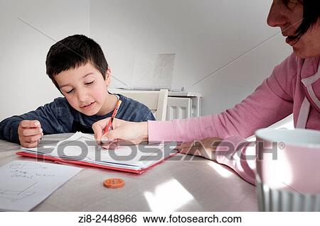 Stock Photograph - Learning at home-private tutor helps boy with homework, UK. Fotosearch