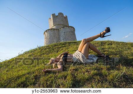Stock Image - Lying before small church young woman in very high heels. Fotosearch