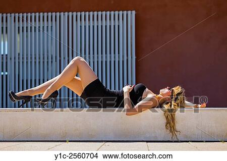 Picture - Lying on back fanciful young woman in Black short dress and high heels. Fotosearch