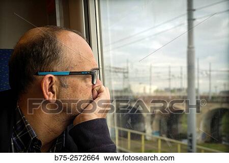 Middle-aged man, with glasses, looking through the window of a train. Italy, Europe View Large Photo Image Picture - Middle-aged man, with glasses, looking through the window of a train. Italy, Europe. Fotosearch