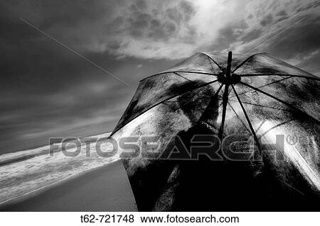 Mujer con paraguas sentada en la playa tras la tormenta. Blanco y. View Large Photo Image Stock Photo - Mujer con paraguas sentada en la playa tras la tormenta. Blanco y.. Fotosearch