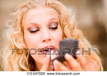 Stock Photo - Portrait of young blonde girl doing make-up. Fotosearch