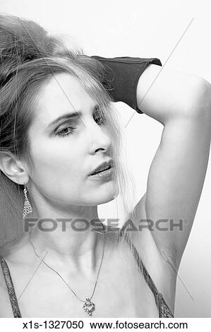 Stock Image - Pretty woman with long hair runs her hands through her hair in a head and shoulders shot.. Fotosearch