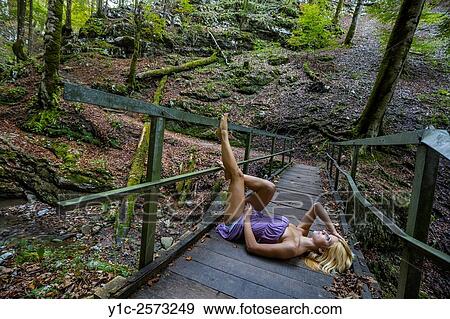 Stock Photo - Pretty young woman lying on back on wooden foot-bridge. Fotosearch