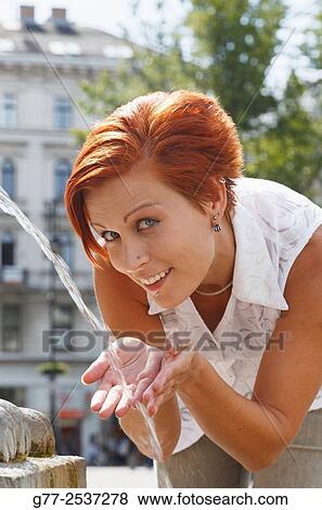 Red hair woman drinking at a fountain View Large Photo Image Stock Photo - Red hair woman drinking at a fountain. Fotosearch