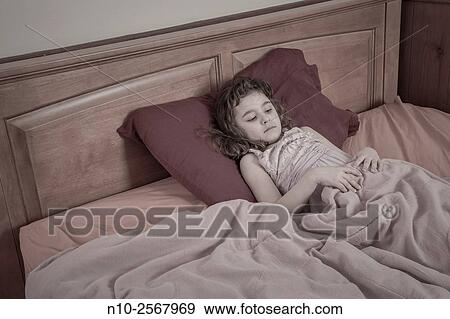 Stock Photo - Six year old girl on her bed.. Fotosearch