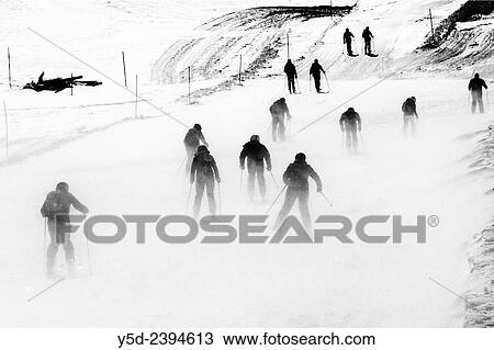 Stock Image - skiers going toward ski slopes after getting out of Metro Alpin at the top of Mittelallalin 3500 m, heavy wind, Saas-Fee, Valais, Wallis, Switzerland.. Fotosearch