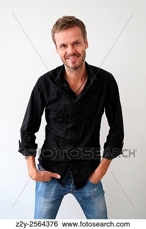 Smily man with black shirt and hands in his pockets looking at the camera. View Large Photo Image Stock Photograph - Smily man with black shirt and hands in his pockets looking at the camera.. Fotosearch