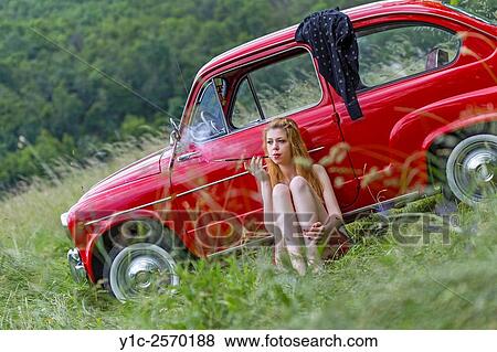 Stock Photo - Smoking young woman before classic Fiat 750 car. Fotosearch