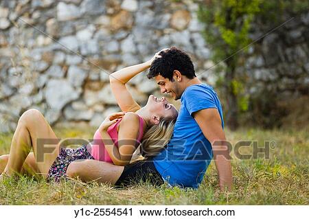 Stock Image - Stock Photo - Happy couple lying on grass in park. Fotosearch