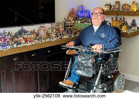 Tilburg, Netherlands. Disabled man in wheelchair due to muscular distrophy posing at home in front of his Dickens Christmas village. View Large Photo Image Stock Photo - Tilburg, Netherlands. Disabled man in wheelchair due to muscular distrophy posing at home in front of his Dickens Christmas village.. Fotosearch