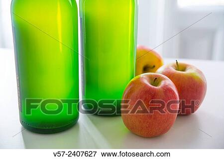 Stock Photo - Two bottles of cider and three apples. Close view.. Fotosearch