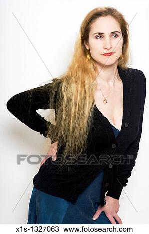 woman in black top and blue skirt with one arm bent at her side and the other resting on her leg looks off. View Large Photo Image Stock Image - woman in black top and blue skirt with one arm bent at her side and the other resting on her leg looks off.. Fotosearch