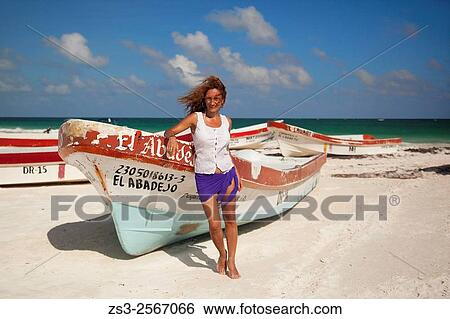 Stock Photograph - Woman posing near the fishing boats on the beach, Tulum, Quintana Roo, Yucatan Province, Mexico, North America.. Fotosearch