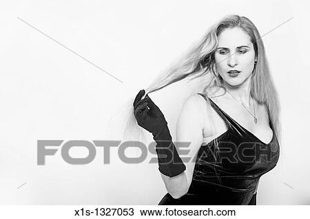 Stock Image - Woman sitting on the floor extends her hair with her right hand and she looks down and away.. Fotosearch