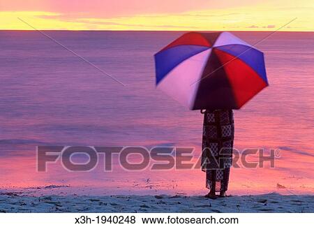 Stock Photo - woman with an umbrella on a beach of Denis island, Republic of Seychelles, Indian Ocean. Fotosearch
