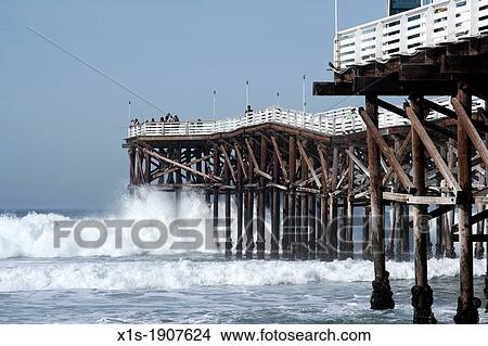 Wooden fishing pier juts into the Pacific Ocean with waves crashing all around. View Large Photo Image Picture - Wooden fishing pier juts into the Pacific Ocean with waves crashing all around.. Fotosearch