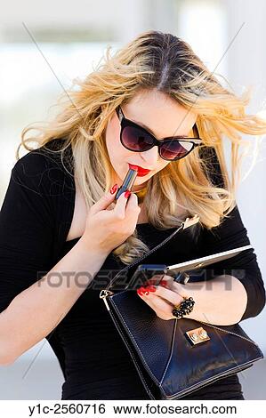 Stock Photograph - Young woman ad-hoc fixing make up on street. Fotosearch