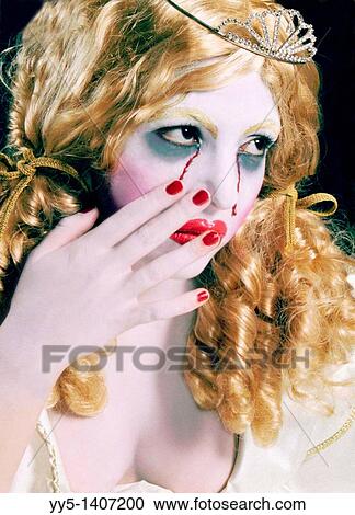 Stock Image - young woman, blonde, crown, crying tears of blood. Fotosearch