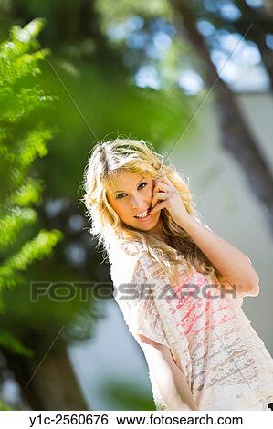Stock Photograph - Young woman flirting with finger in mouth looking at camera. Fotosearch