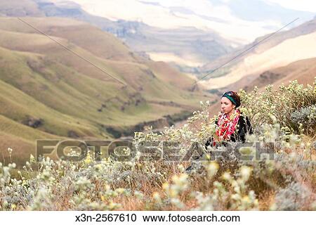 Young woman sitting amongst the wildflowers with rolling hills in the background in Sani Pass, between South Africa and Lesotho. View Large Photo Image Stock Image - Young woman sitting amongst the wildflowers with rolling hills in the background in Sani Pass, between South Africa and Lesotho.. Fotosearch